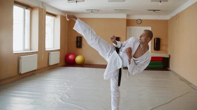 Karate man fighter exercising punching and kicking techniques during training at the dojo.Martial Art Concept