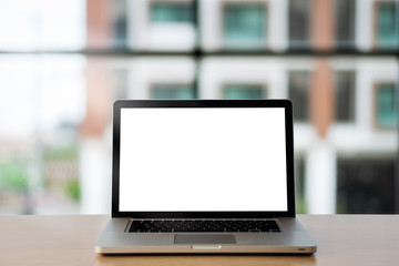 laptop showing blank screen on work table front view at with glass wall as background.