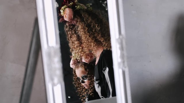Woman and little girl have blond curly hair. People have wreath made of flowers. It is mirror reflection of two people.