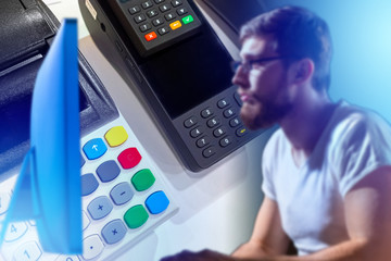 Setting up cash registers. Concept - hacker breaks into cash registers. Man next to the cash register equipment. Guy is working with a computer. Concept - programmer develops payment acceptance.