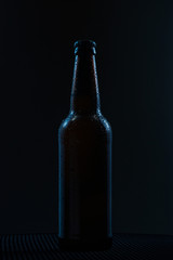 beer bottle with drops drink without label on a dark background