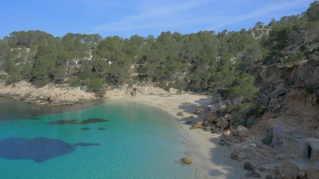 Aerial Drone forward view of paradise white beach and turquoise water with couple walking, Ibiza, Spain