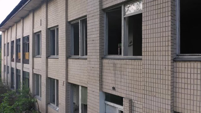 Abandoned building exterior with broken windows. Aerial crane elevator shot