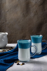 Latte Matcha Dalgona. Hot fresh milk with blue butterfly pea flowers. On a light gray background. Vertical orientation