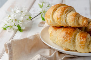 Delicious breakfast with croissants and coffee and spring flowers on the white wooden