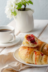 Delicious breakfast with croissants and coffee and spring flowers on the white wooden