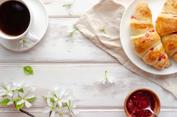 Delicious breakfast with croissants and coffee and spring flowers on the white wooden