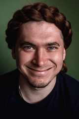 the guy is smiling. happy. smile to the ears. close-up . braid on the head. guy hairstyle