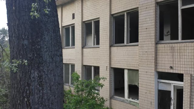 Abandoned building exterior with broken windows. Aerial side view. 