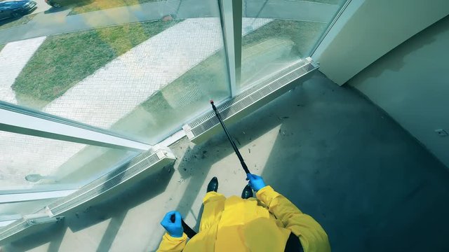 Male cleaner sprays window with antiseptics.