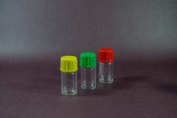 pequeñas botellas de vidrio de distintos colores y formas con tapas de color rojo, verde y amarillo