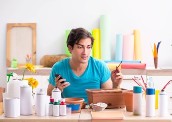 Young man decorating pottery in class