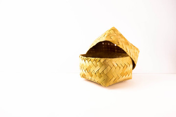 Small hand-woven bamboo wicker container with lid partly opened over white. Selective focus on container. Usually use for food storage.