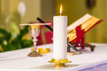 lit candle illuminates chalice with wine and ciborium with the host, ready for the communion of the faithful