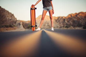 Beautiful girl with long legs enjoys a ride on a longboard at summertime. Outdoors sports activities. © Nick Starichenko