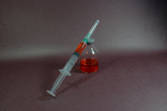 peque&ntilde;a jeringa y aguja con medicina al lado de peque&ntilde;as botellas