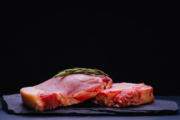 Raw steak sliced cow loin with herbs salt and pepper black stone background close up ingredients for cooking. Top view