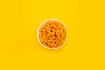Pyramid of pasta, noodles spiral in the plate on a yellow background