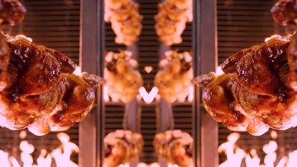Symmetrically aligned chickens on spikes rotating in rotisserie between walls of flames