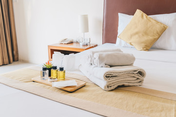 Group set of free hotel amenities (such as towels, shampoo, soap, gel etc) on the bed. Hotel amenities is something of a premium nature provided in addition to the room when renting a room.
