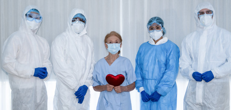caucasian senior coronavirus covid-19 infected patient and medical doctor team with medical staffs posting for photography together after rtreament and ecover from desease at hospital