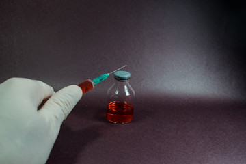 pequeña jeringa y aguja con medicina al lado de pequeñas botellas