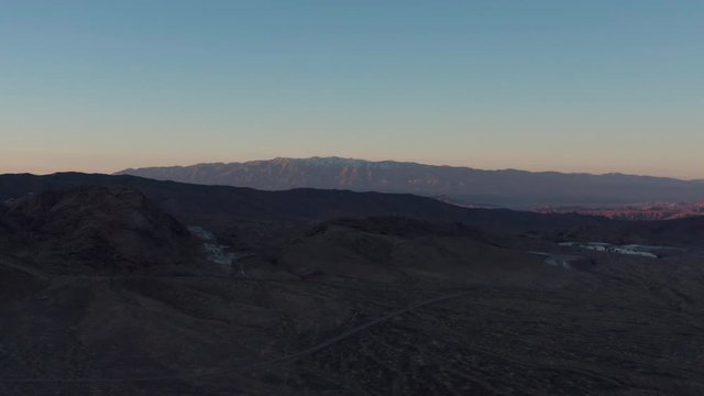 An aerial tracking shot of morning sunlight illuminating the Avawatz Mountains and Dumont Dunes at dawn. The Amargosa River valley is seen in the foreground. Drone take off, landing and operation cond