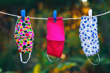 face masks with different style prints hang and dry on clothespins outdoors at sunset