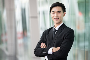 Confident handsome business man.  in black suit standing in office, young asian man smilling