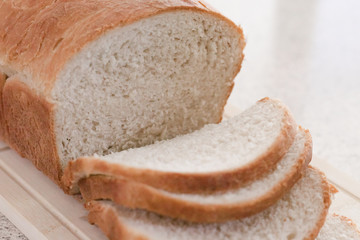 Fresh baked, homemade bread sliced on a wooden cutting board on a home's kitchen counter top.