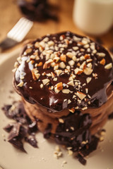 A view of delicious cocoa pancakes with dark chocolate and powdered sugar on a wooden table