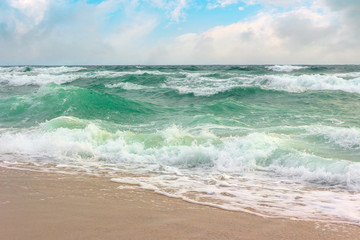 storm on the sandy shore. dramatic ocean scenery with cloudy sky. rough water and crashing waves