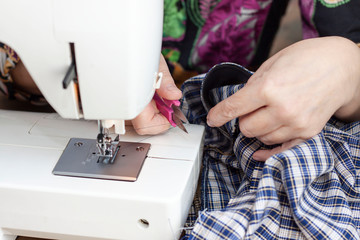 Seamstress's hands cut the thread near the sewing machine. The sewing process