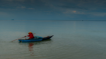 Older man fishing on smal boat in calm seas on the Gulf of Thailand