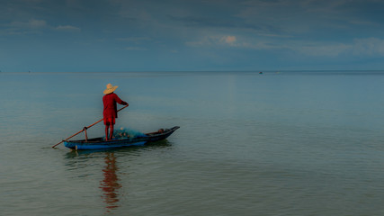 Fototapeta premium Older man fishing on smal boat in calm seas on the Gulf of Thailand