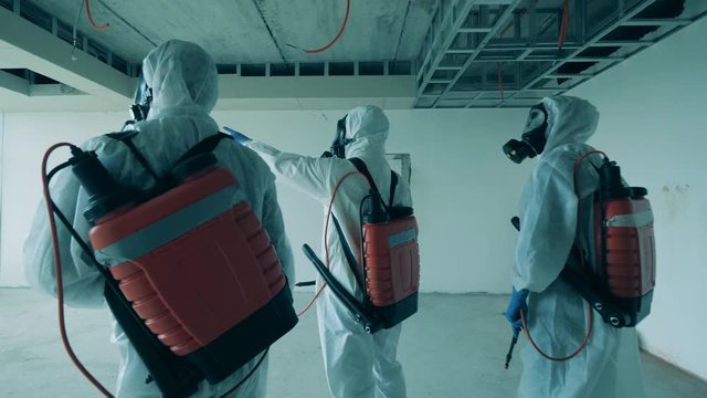 Three cleaners check unfinished building before disinfection.