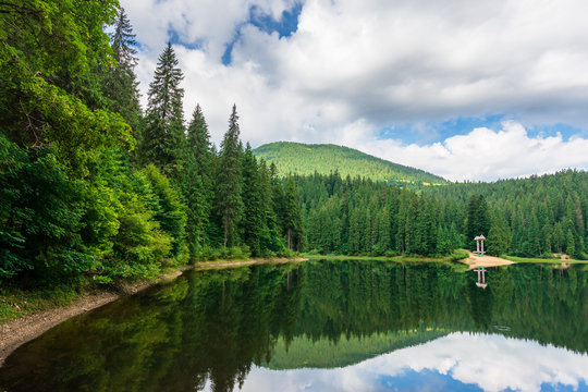 scenery with forest reflecting in the lake. Synevyr National park is a popular destination of Ukrainian Carpathians. clouds above the distant mountain. wonderful summer weather