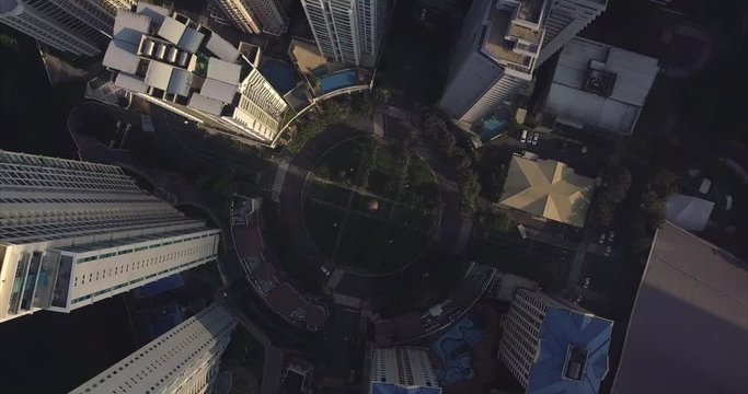 Zoom out orbiting aerial flight over roundabout intersection in urban area. Drone, 4K.