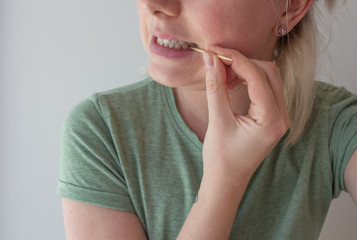 girl picks her teeth with a toothpick. Dental care concept. Harm from toothpicks