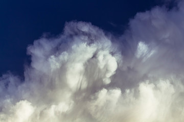 White fume clouds on dark blue sky with shadows and light