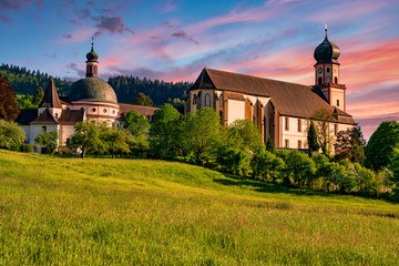 The Benedictine monastery St. Trudpert (Kloster Sankt Trudpert) in the Black Forest in Muenstertal at sunset in front of a colourful sky - obrazy, fototapety, plakaty