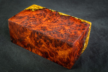 Casting epoxy resin gold with nature burl BURMA PADAUK wood cube on black background