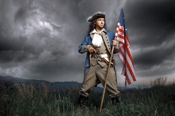 Man in United States War of Independence soldier costume with flag posing in forest. 4th July...