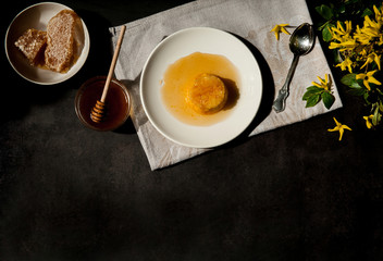 Home cooking. Delicious rice pudding with carrots on a white plate with sweet Golden honey and spring sprigs of forsythia on a dark concrete background. The soft sunlight. Free space.