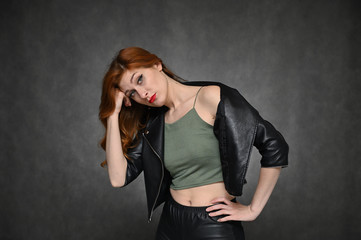 The model shows different emotions by changing poses. Portrait of a young pretty woman with beautiful hair and a great make-up in a green T-shirt and black jacket on a gray background.