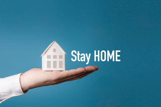 White home in man's hand on isolated blue background with Stay home text for stay safe from Corona-19