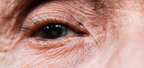 Fototapeta premium Close-up of one eye of an elderly Asian person with wrinkles around the eyes.