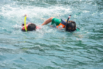 Asian man and Boy wearing a life jacket and scuba diving in the sea.