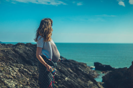 Pregnant woman standing on rock by the sea in the spring