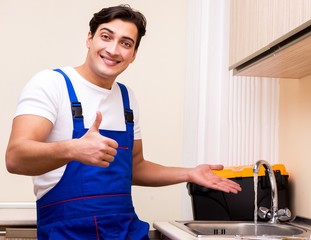 Young repairman working at the kitchen
